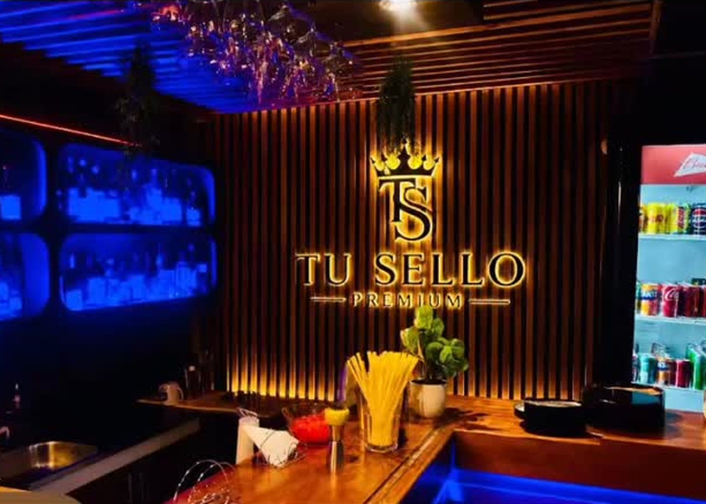 Barra iluminada con neón azul y el logo de Tú Sello Premium